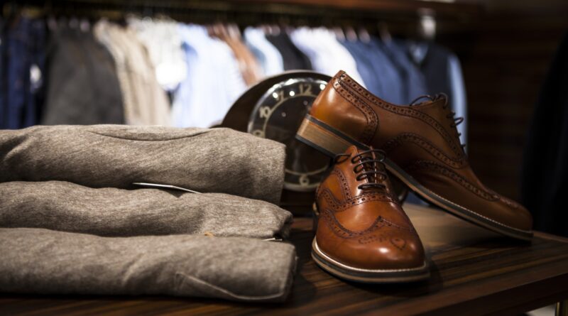 Pair of Brown Leather Wingtip Shoes Beside Gray Apparel on Wooden Surface