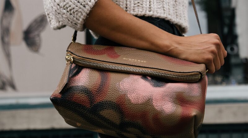 woman holding brown and pink floral leather crossbody bag